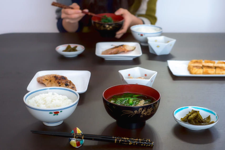 白米、味噌汁、焼き魚、小鉢、漬物の一汁三菜の和食を食べている。