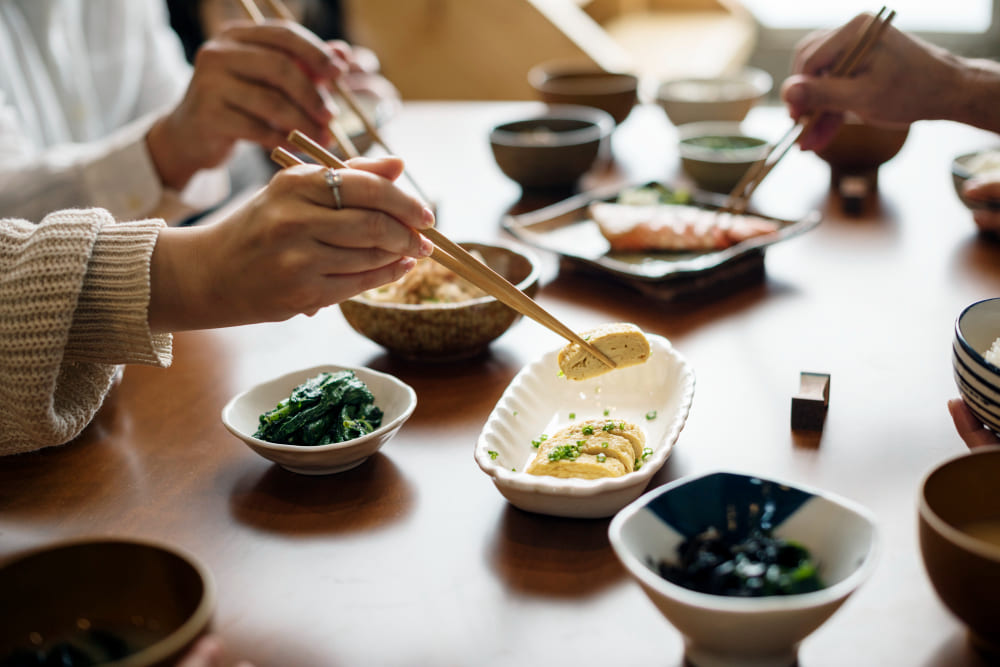 テーブルに並んだ一汁三菜の和食を食べている。