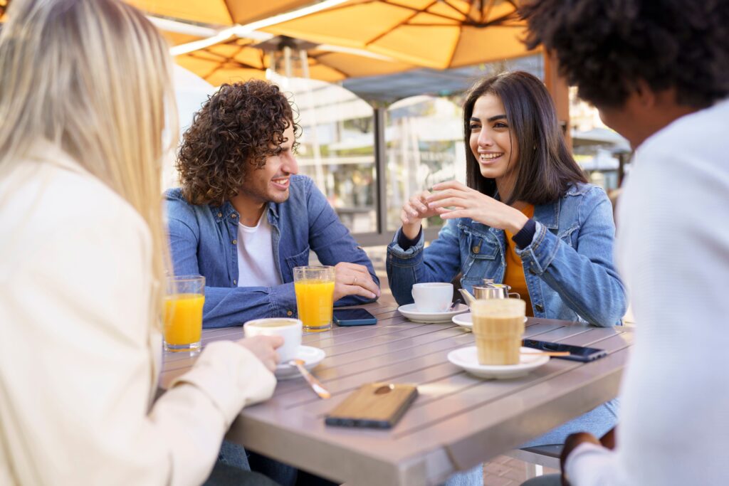 カフェのテラス席でコーヒーを飲みながら談笑している。