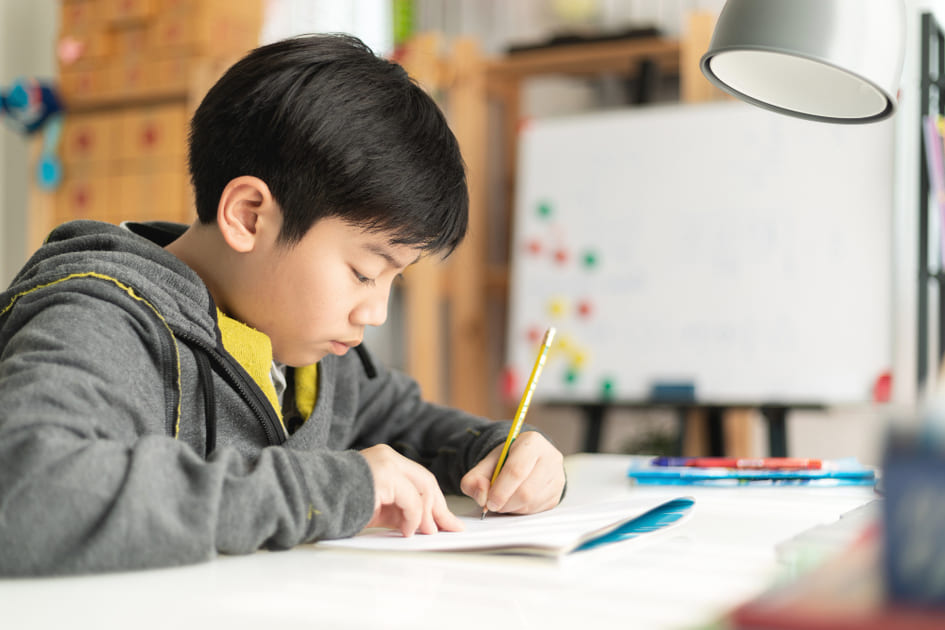 男子小学生が基礎学力をつけるために机に座り勉強している。