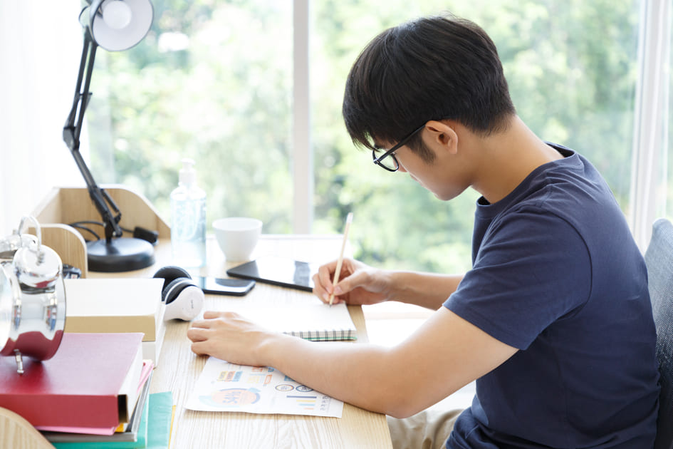 机に向かい、受験勉強に勤しむ男子高校生。
