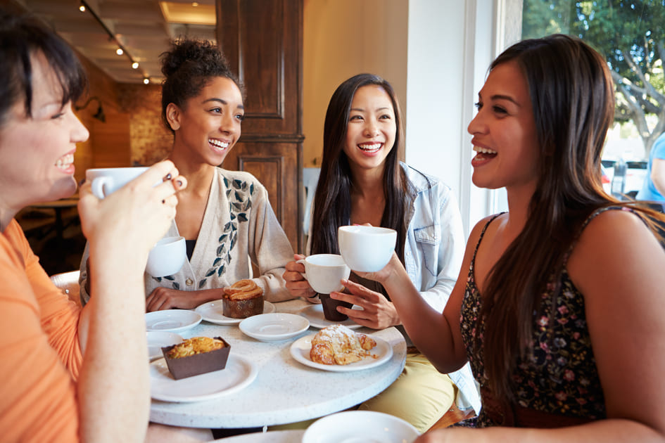 カフェでコーヒーを飲みながら朝食を楽しんでいる美しい女性たち。