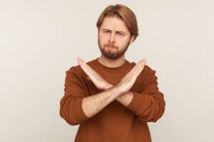 両腕を胸の前でばってんに組み、NGを示す若い男性。