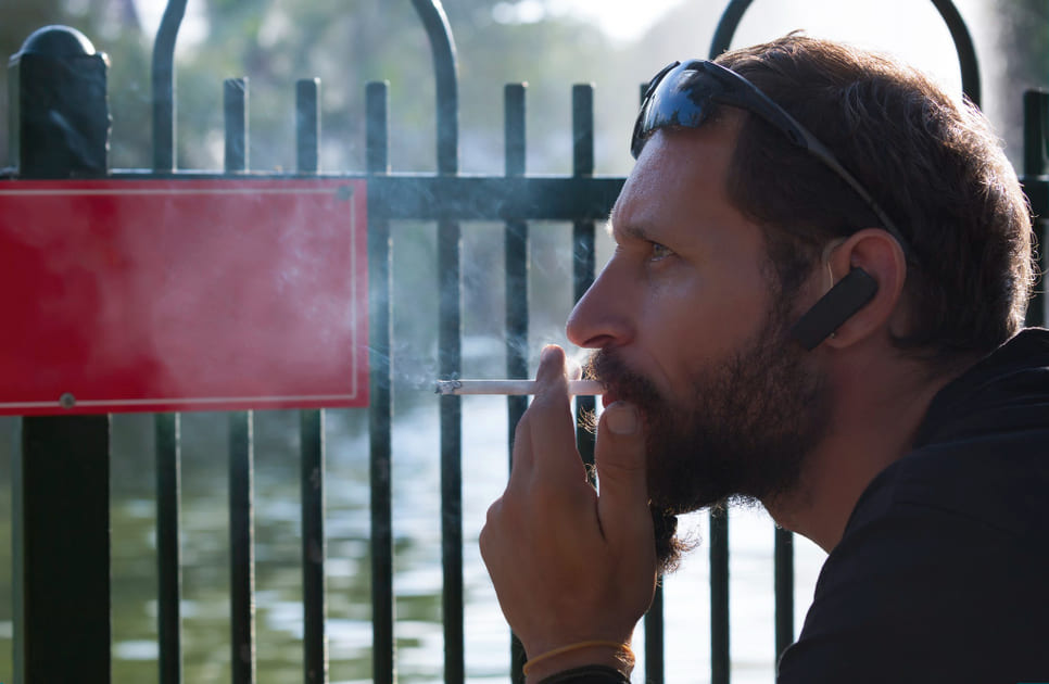 喫煙エリアでたばこを吸う、オーストラリアの男性。