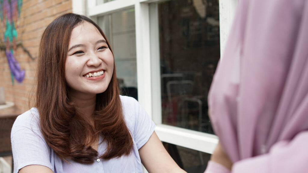 笑顔であいさつをする、日本人の女子学生。