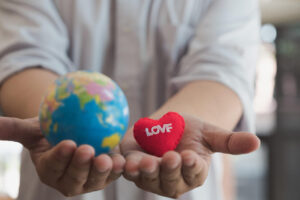 国際恋愛を表現している地球儀とハートのモチーフを両手に乗せている男性