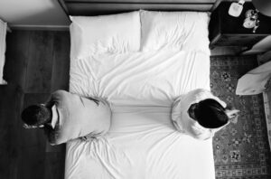 セックスレスに悩む夫婦が背中合わせに座るベッドのイメージ