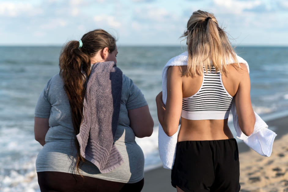 ふくよかな女性とスレンダーな女性が浜辺で立ち話をしている。